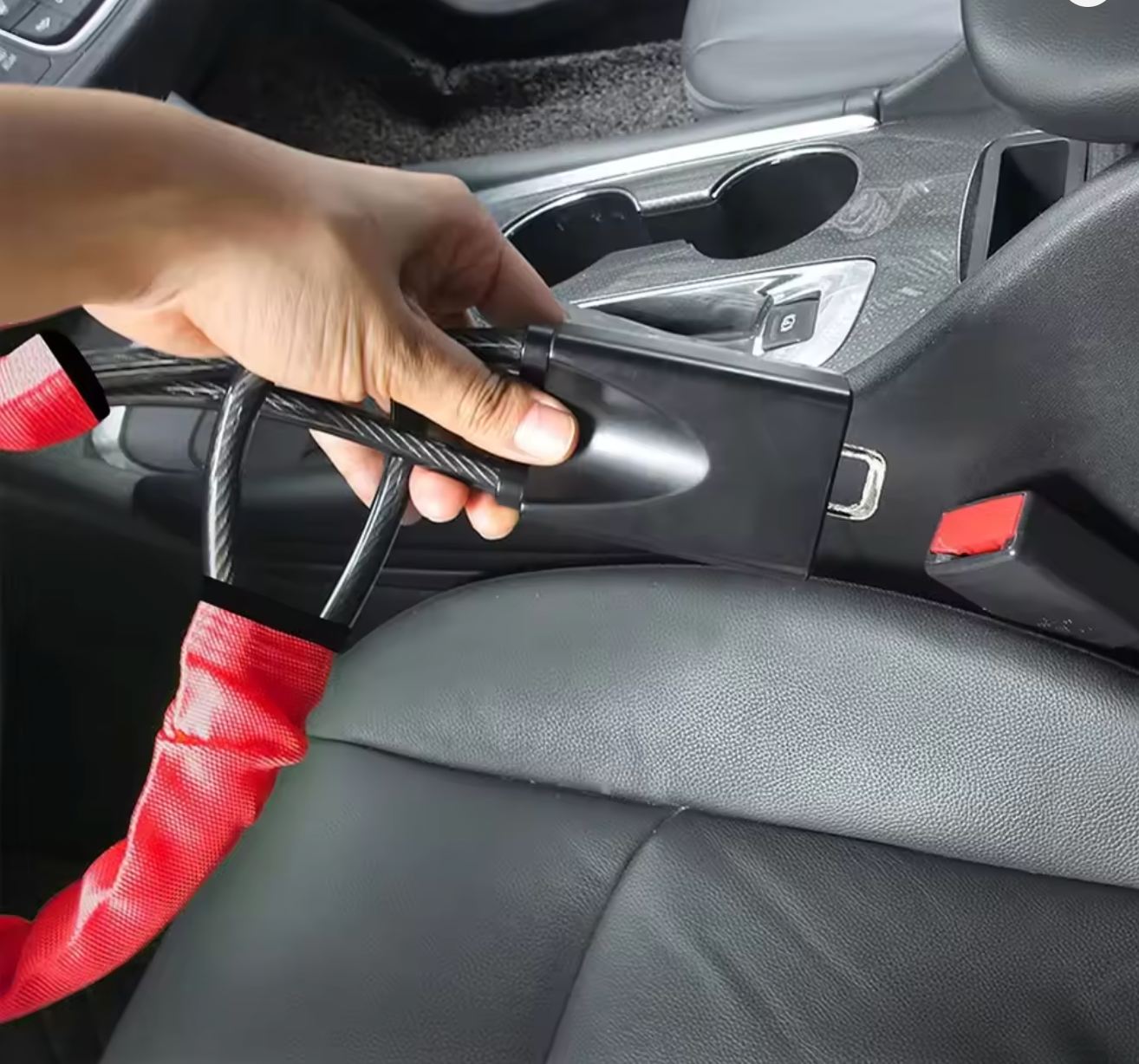 Person inserting a yellow cabled car steering wheel lock into car seatbelt socket inside a vehicle