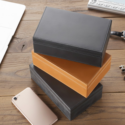 Stack of black and brown signal blocking Faraday boxes that prevent car theft by blocking signal cloning relay attacks on a wooden surface with a phone and other items.