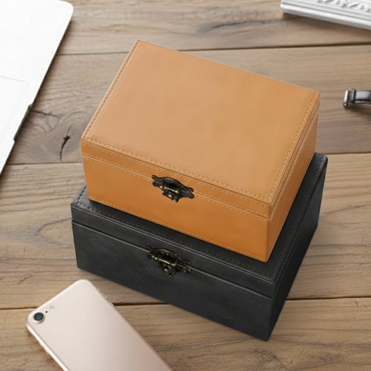 Two stacked signal blocking Faraday boxes for car keys to prevent keyless car theft, one orange and one black, on a wooden surface with a phone in the foreground.