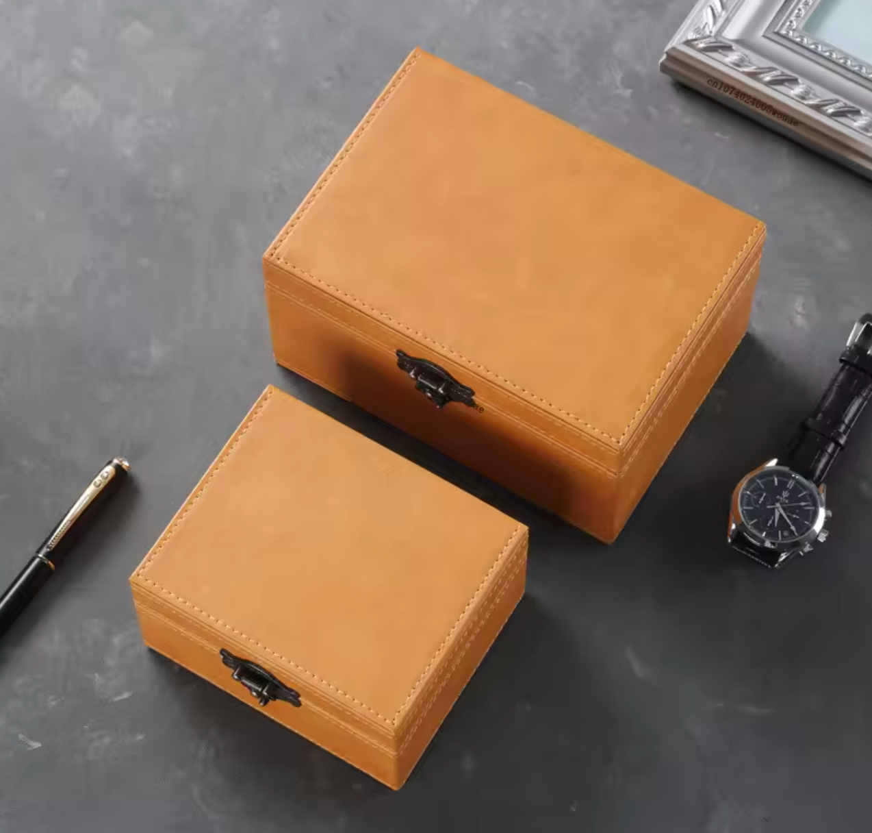 Two brown signal blocking Faraday box used to prevent car theft by blocking relay attacks with a black clasp on a grey surface.